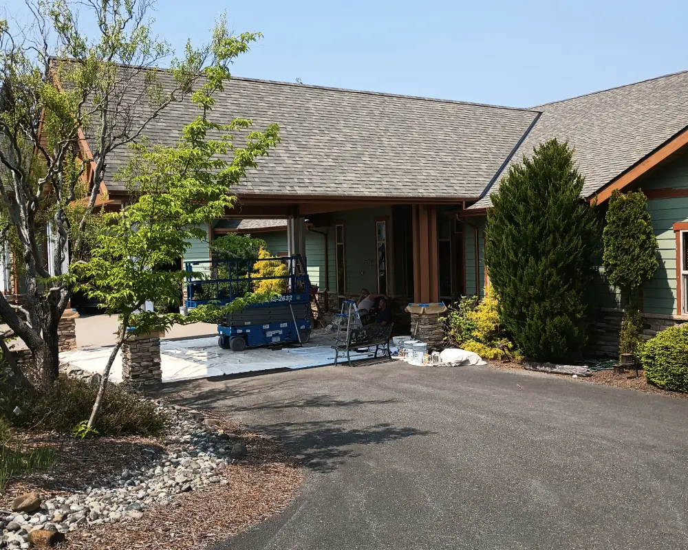 A house with a driveway and trees in the background.