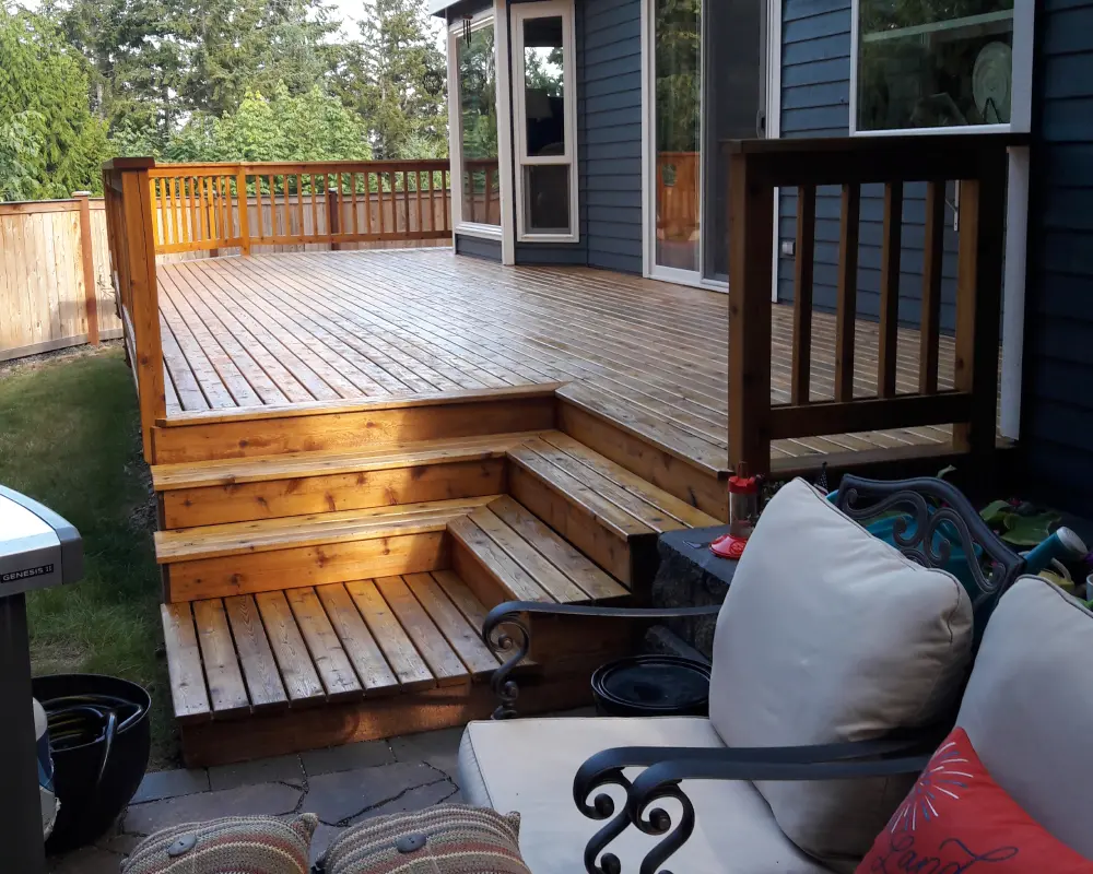 A wooden deck with steps and stairs leading to the back patio.