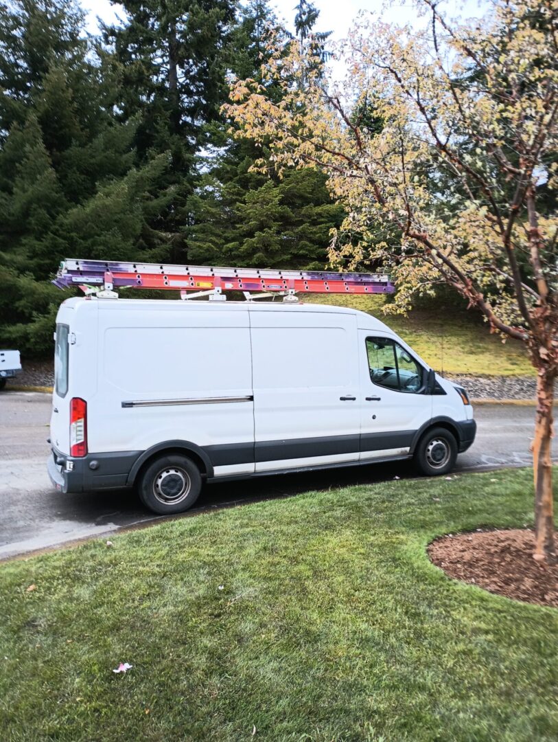 A white van with a ladder on the back of it.