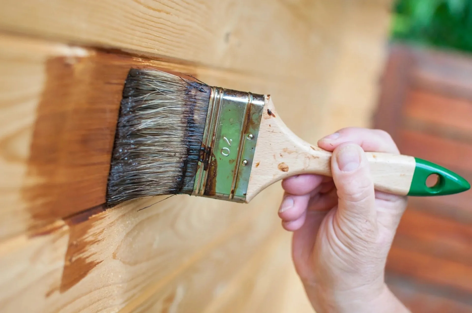 A person holding a paintbrush and painting the side of a wall.