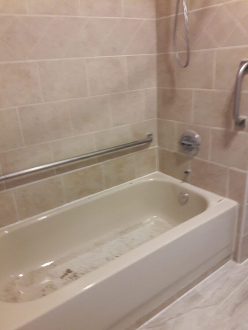 A bathtub and shower in a bathroom with tile.