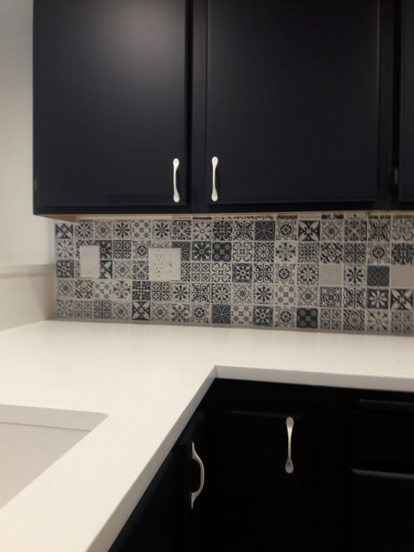 A kitchen with black cabinets and white counter tops.