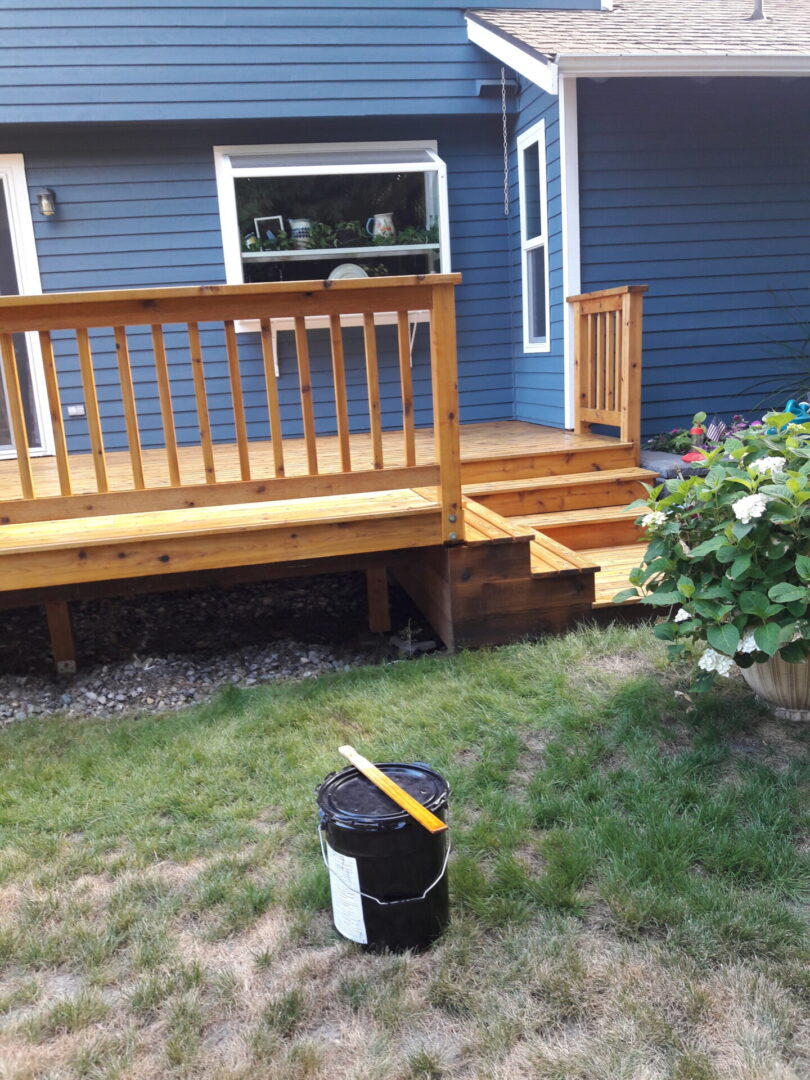 A house with a blue deck and a black trash can.