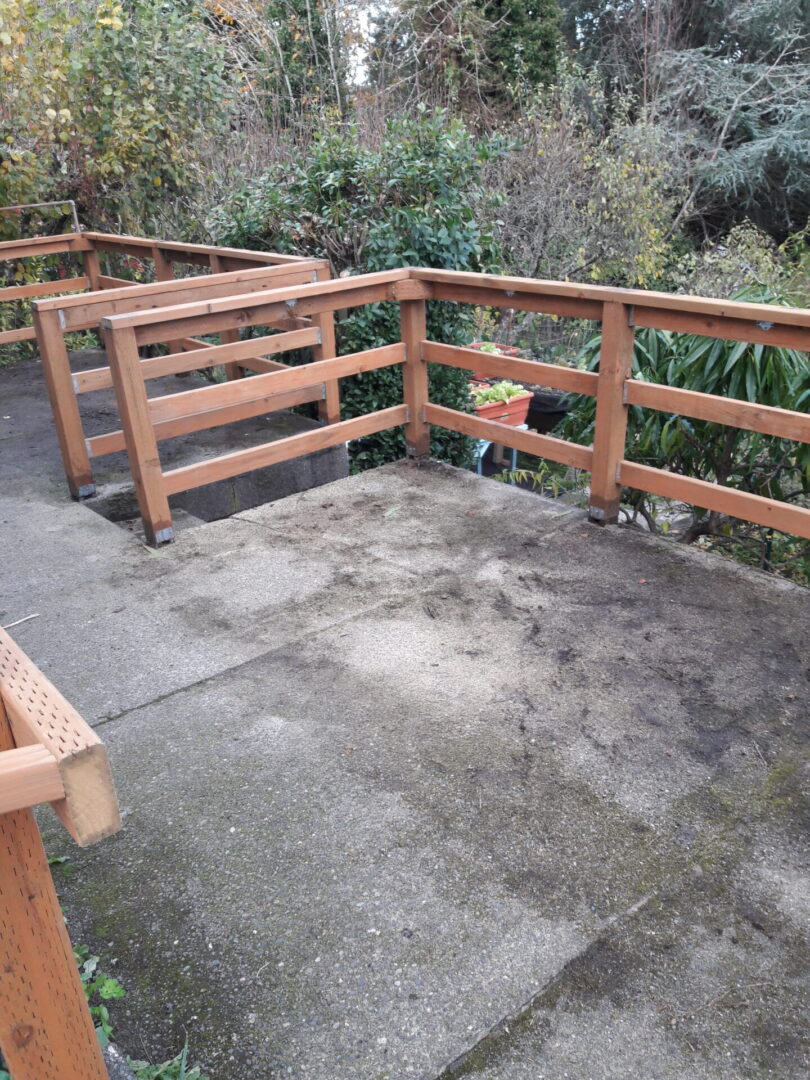 A wooden deck with railing and concrete floor.