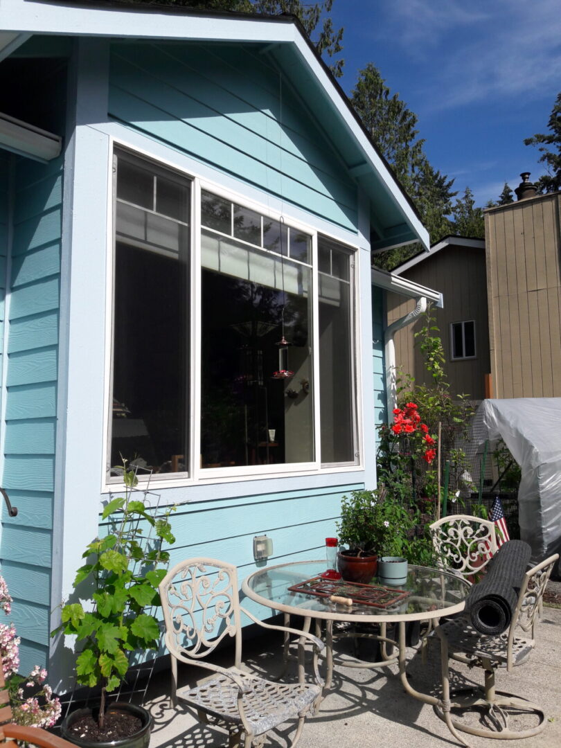 A blue house with a table and chairs outside of it