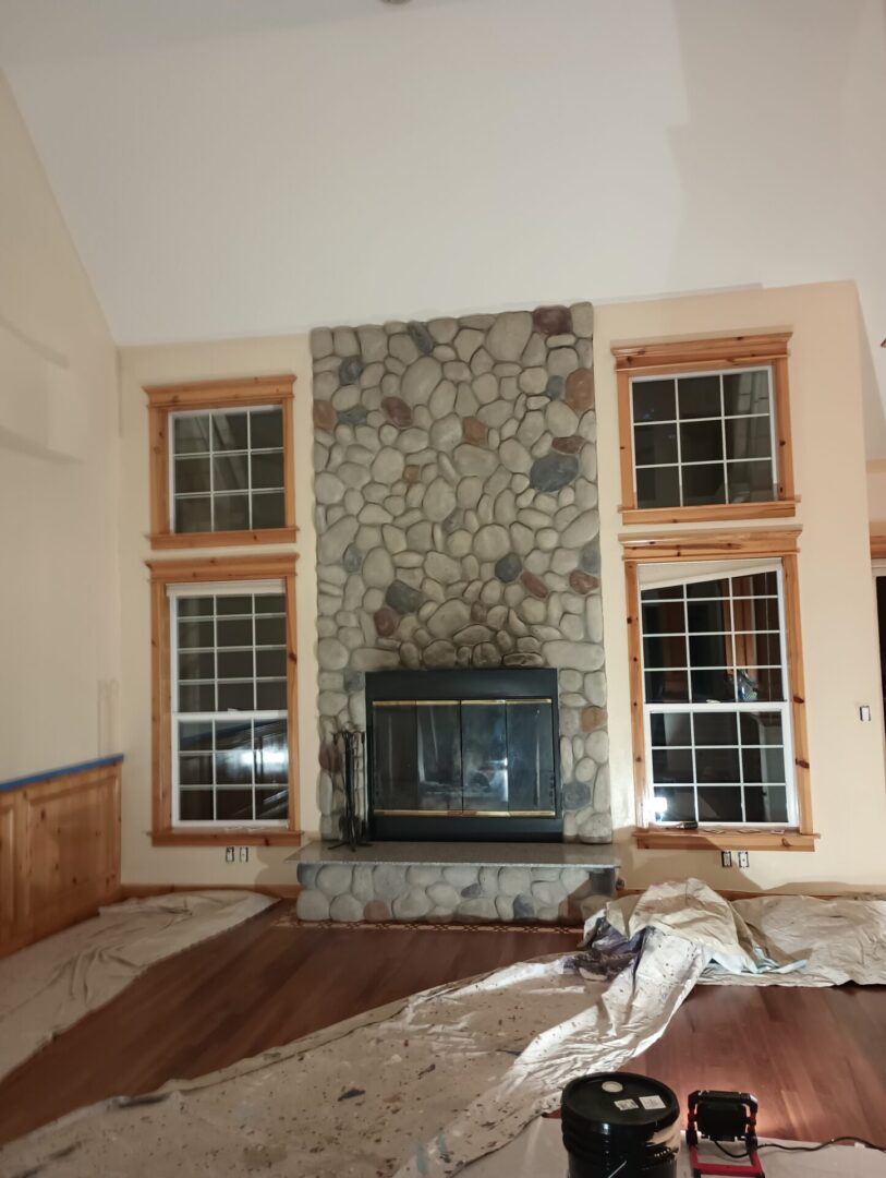 A fireplace in the middle of a room with two windows.