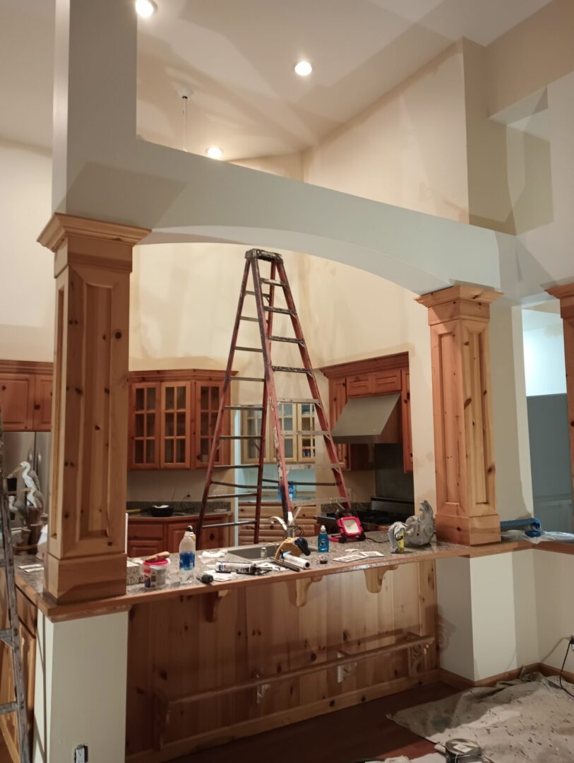 A ladder is in the middle of a kitchen.