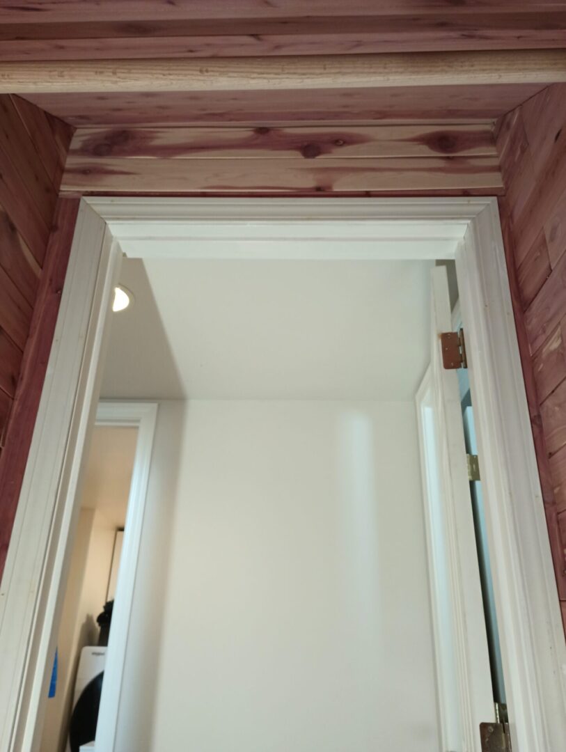 A door way with a wooden ceiling and white walls.