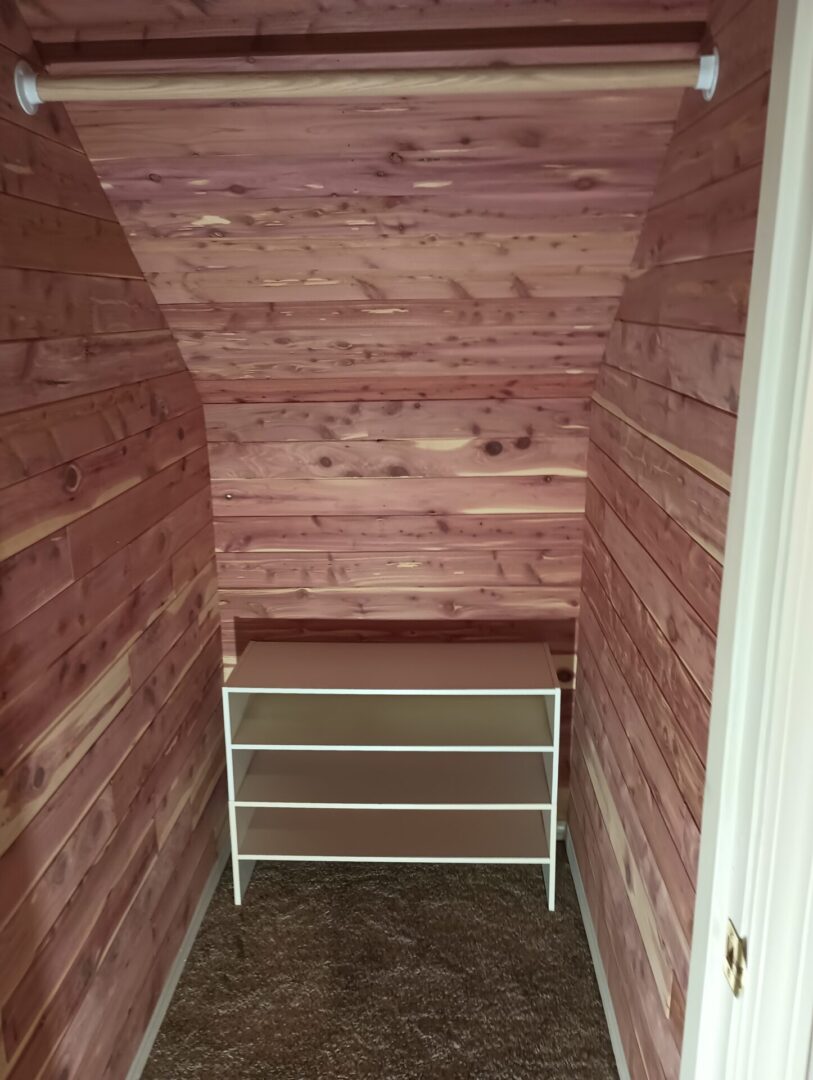 A small room with wooden walls and a shelf.