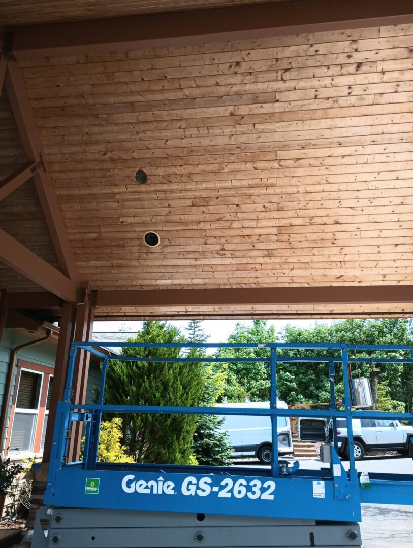 A blue metal fence in front of a wooden ceiling.