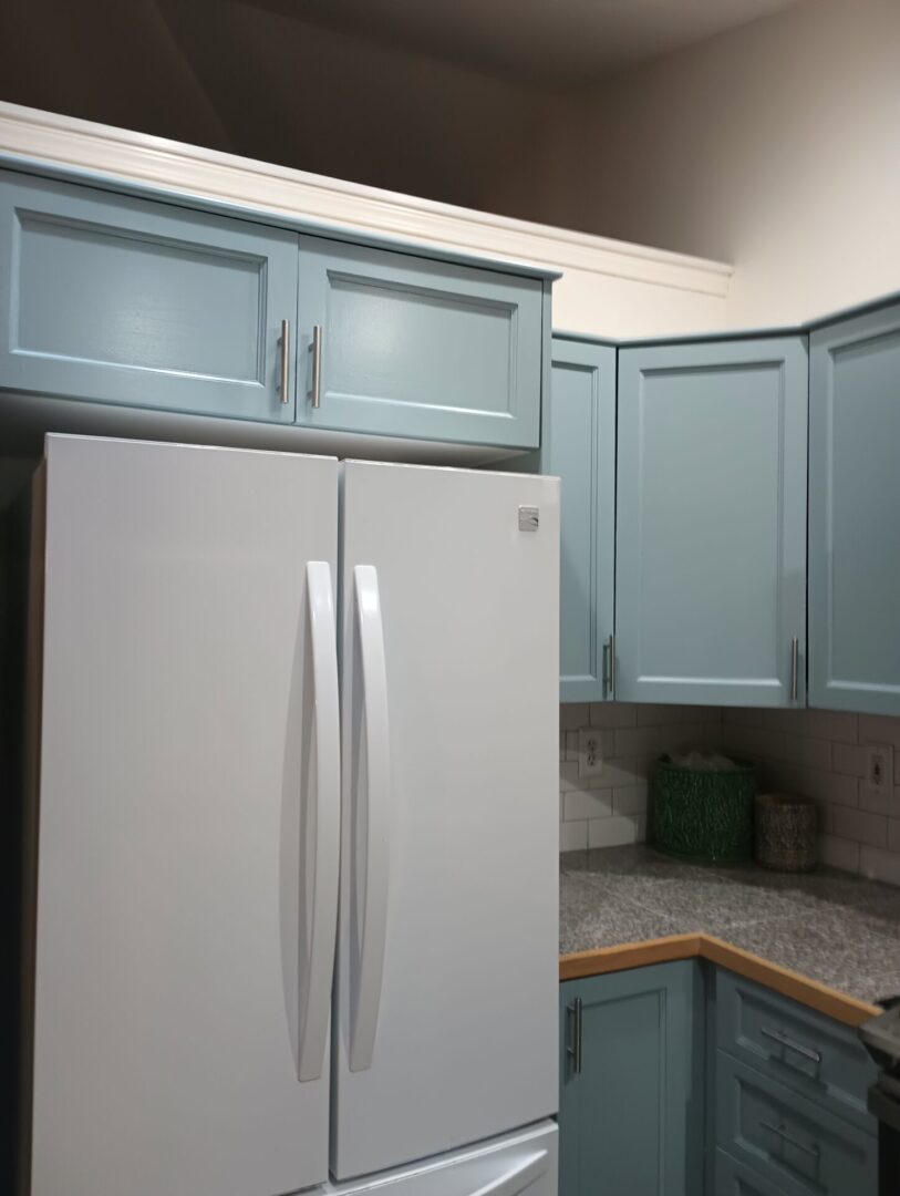 A kitchen with blue cabinets and white appliances.