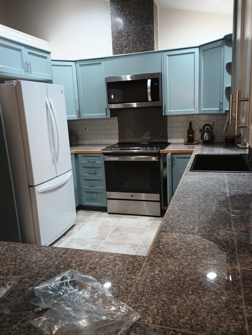 A kitchen with blue cabinets and white appliances.