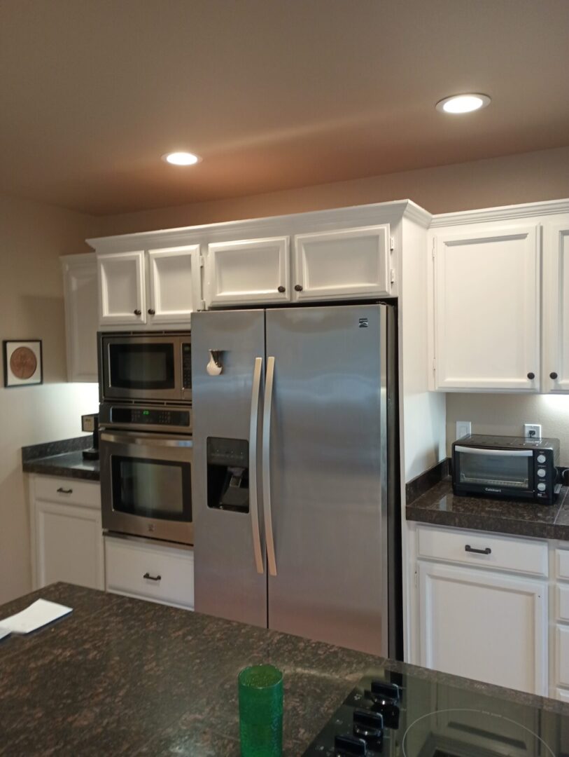 A kitchen with white cabinets and black counter tops.