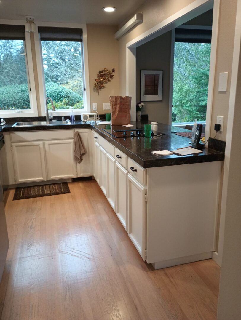 A kitchen with white cabinets and black counter tops.