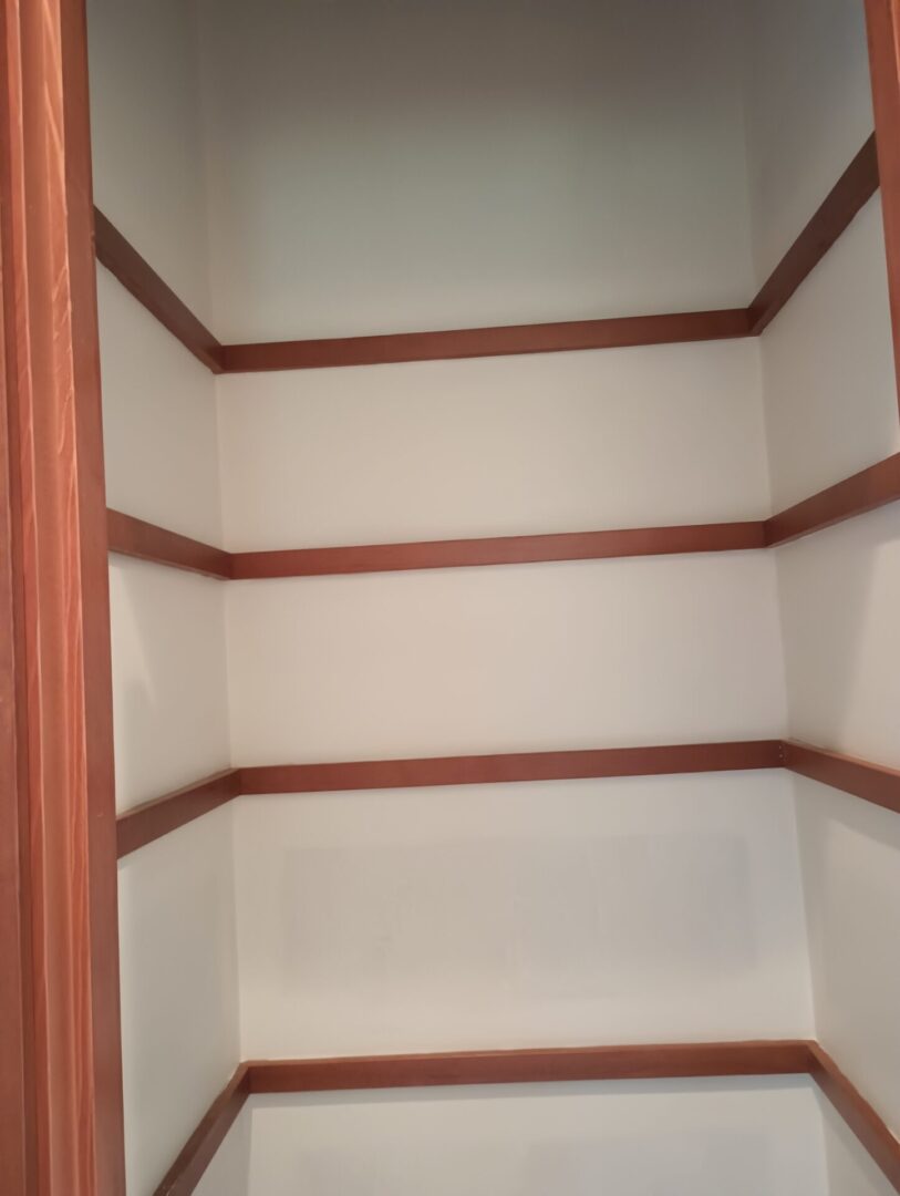 A closet with shelves and wood trim in it