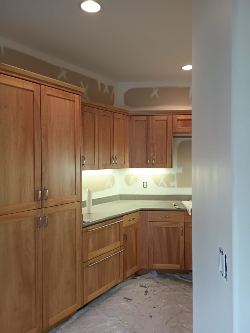 A kitchen with wooden cabinets and white counters.